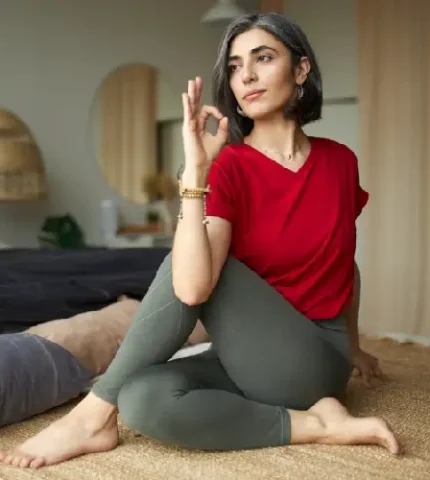 Mature woman performing a seated yoga twist, demonstrating mindful physical activity for menopause management.