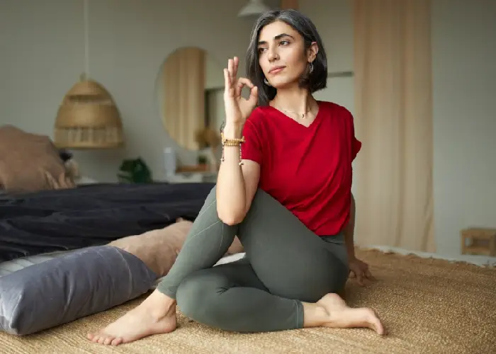 Mature woman performing a seated yoga twist, demonstrating mindful physical activity for menopause management.