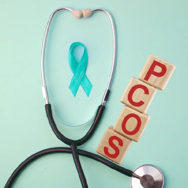 Stethoscope, teal ribbon and wooden blocks spelling PCOS, representing PCOS meal planning and diet support